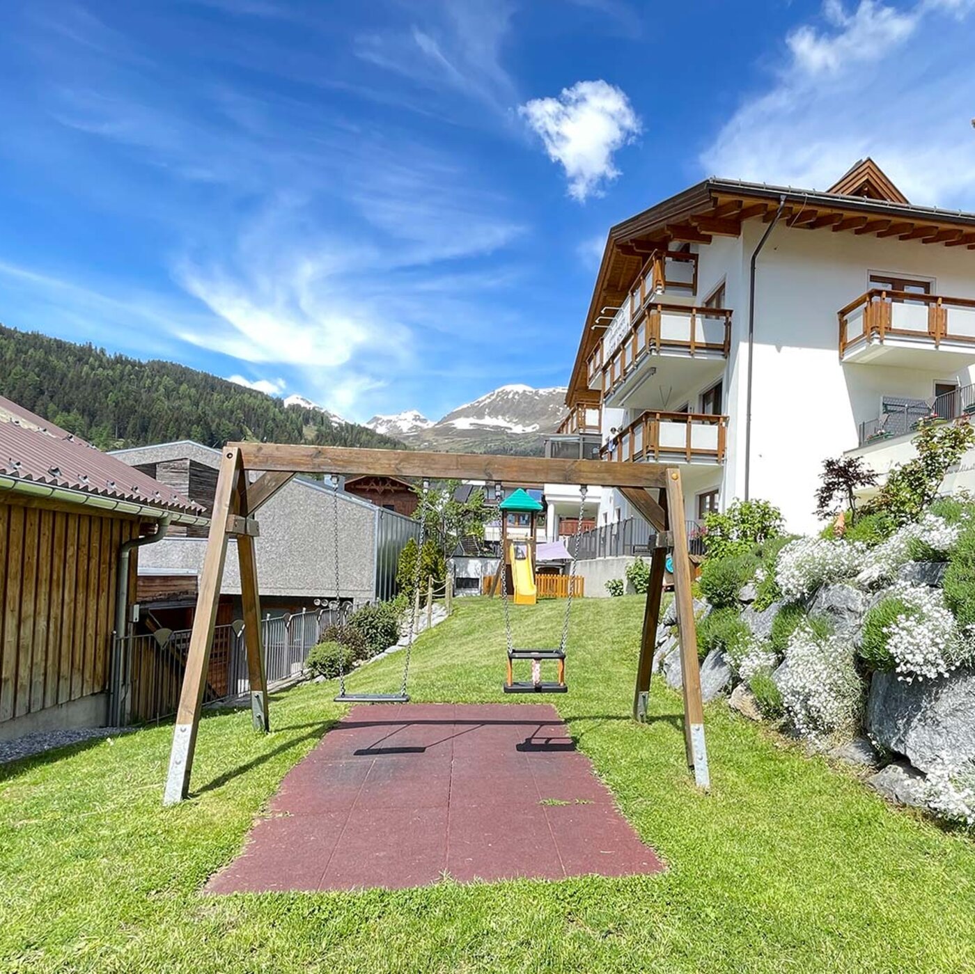 Gartenweg zum Haus Montjola in Serfaus mit Blumen, Liegewiese und Bergblick.