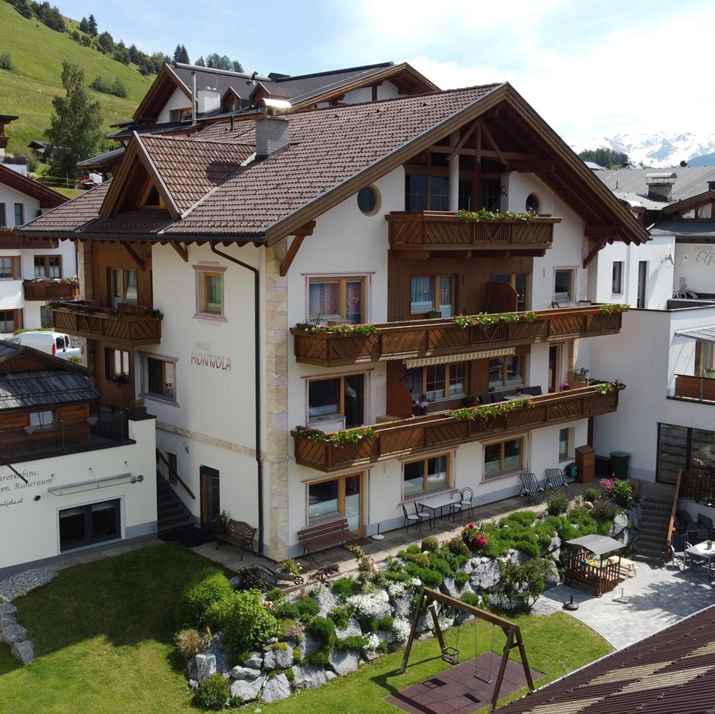 Haus Montjola in Serfaus mit Balkonen, Garten und Blick auf die Tiroler Berglandschaft.