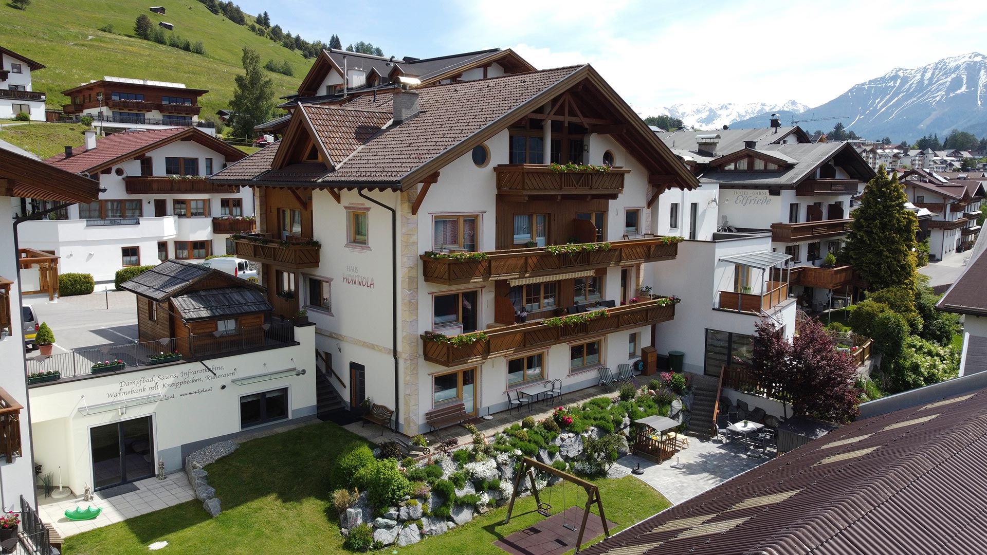 Haus Montjola in Serfaus mit Balkonen, Garten und Blick auf die Tiroler Berglandschaft.