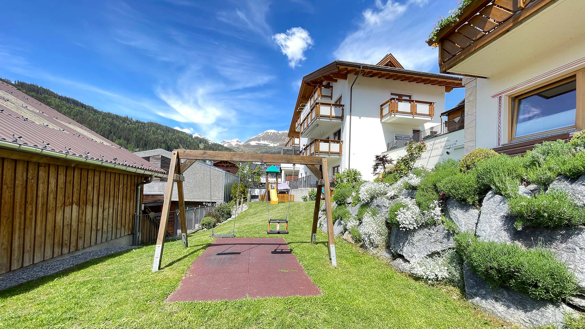 Gartenweg zum Haus Montjola in Serfaus mit Blumen, Liegewiese und Bergblick.