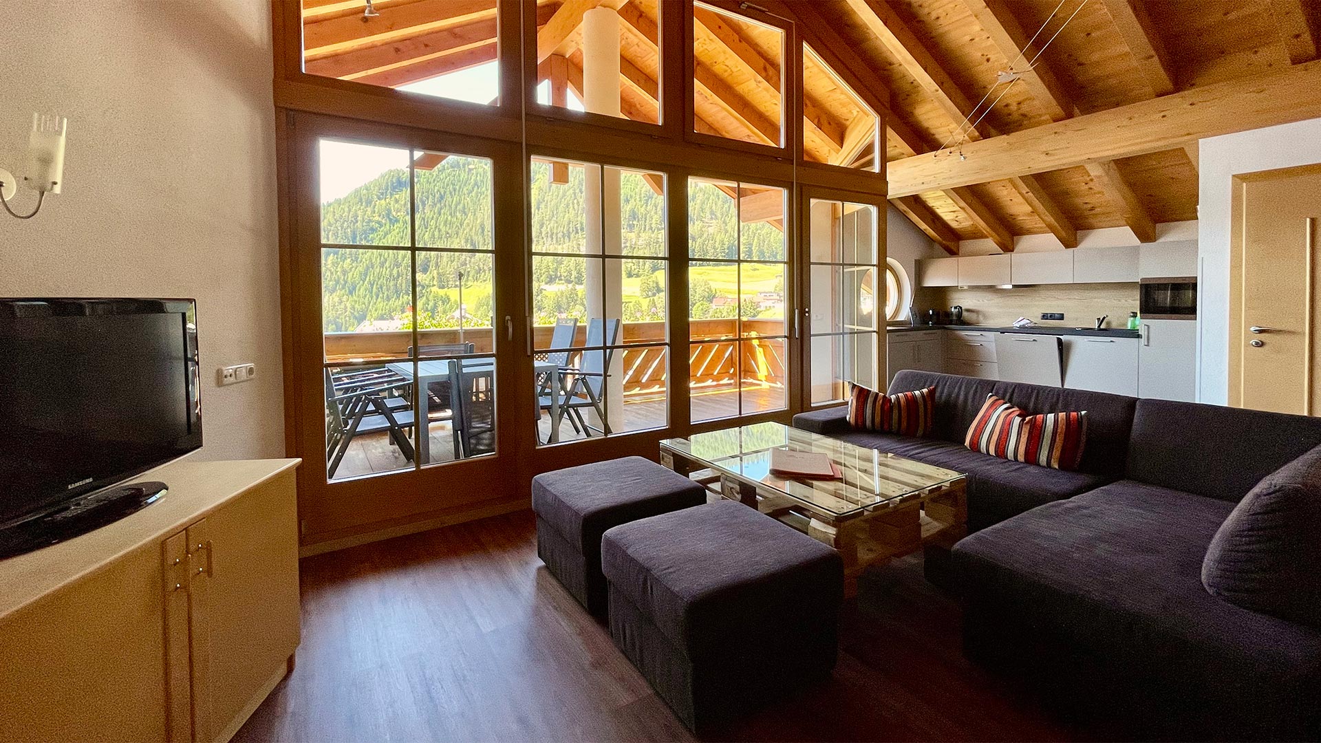Wohnzimmer im Haus Montjola Serfaus mit Sofa, Holzdecke und Panoramafenstern.