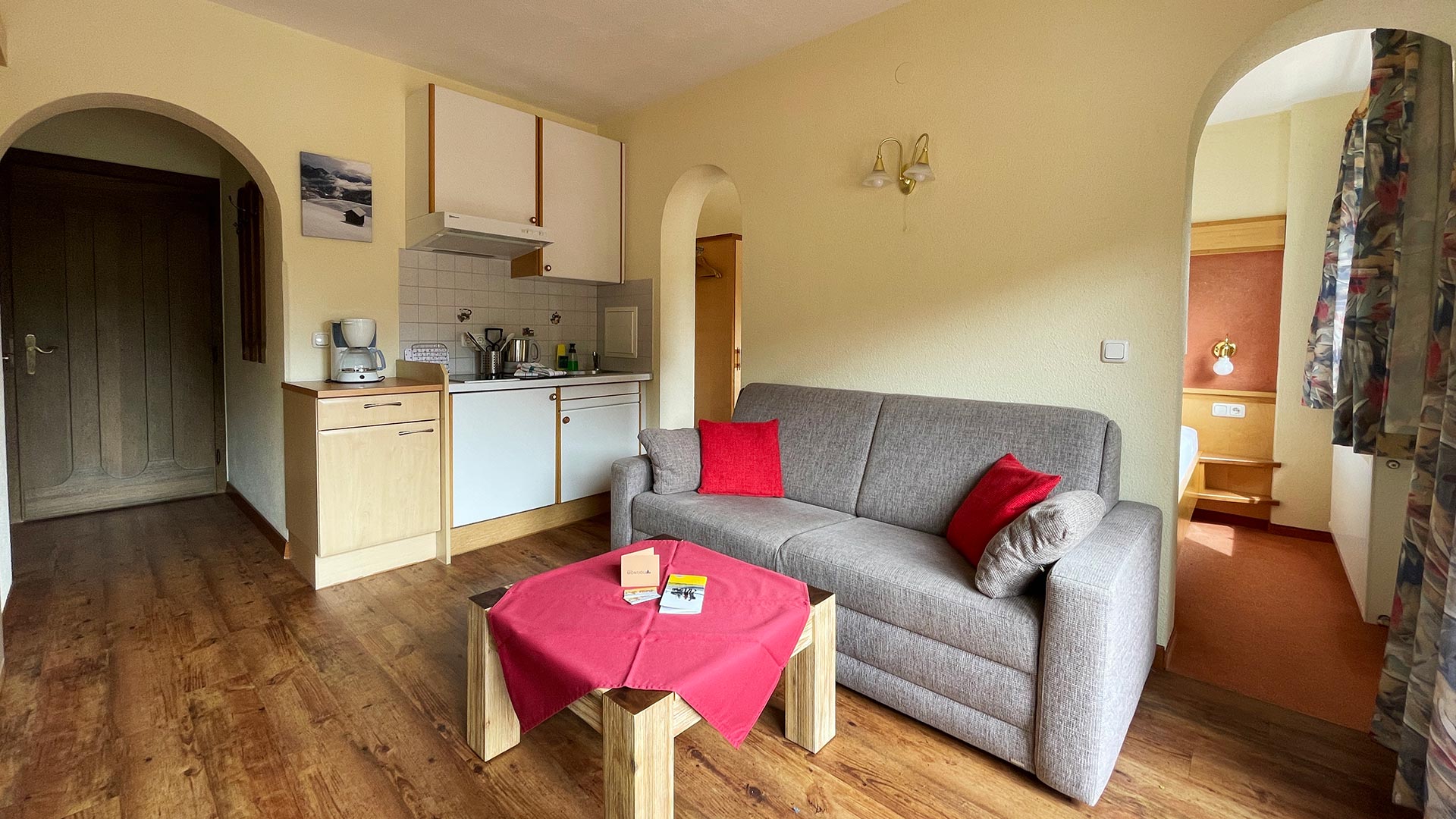 Wohnbereich im Haus Montjola Serfaus mit Küchenzeile, Sofa und Esstisch.
