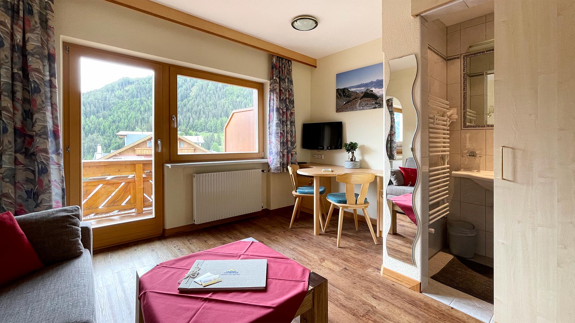 Wohnbereich im Haus Montjola Serfaus mit Esstisch, Sofa und Balkonblick.