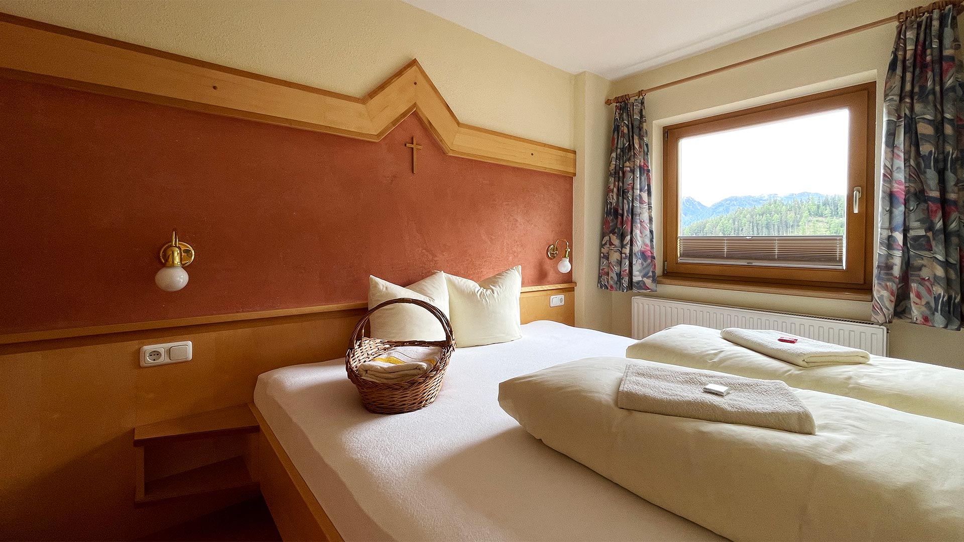 Schlafzimmer im Haus Montjola Serfaus mit Doppelbett, Holzelementen und Fensterblick.