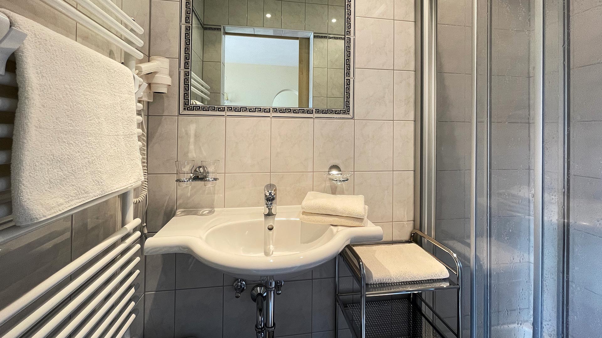 Badezimmer im Haus Montjola Serfaus mit Waschbecken, WC, Dusche und Handtuchheizkörper.