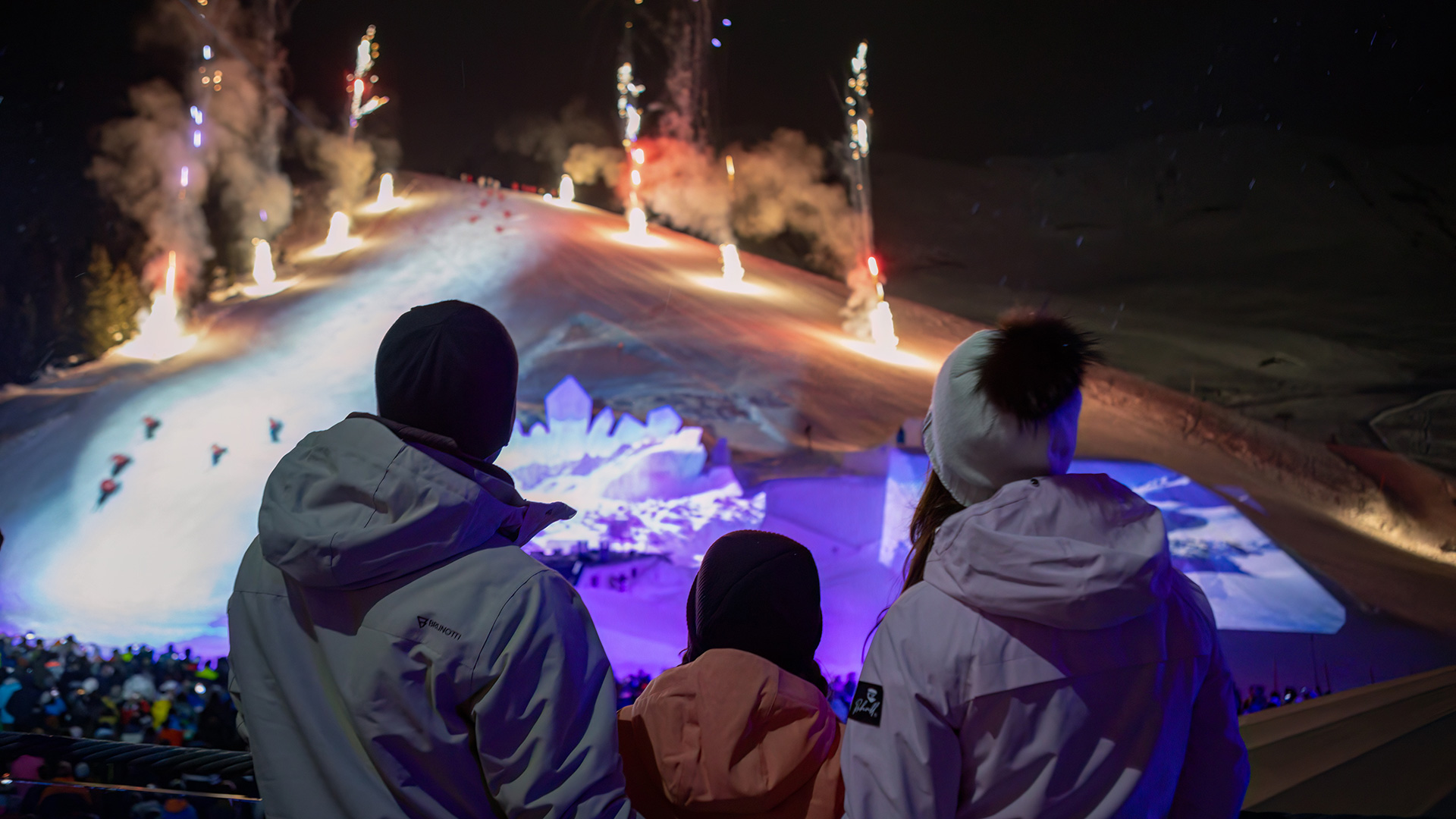 Familie beobachtet abends eine beleuchtete Schneeshow in Serfaus.